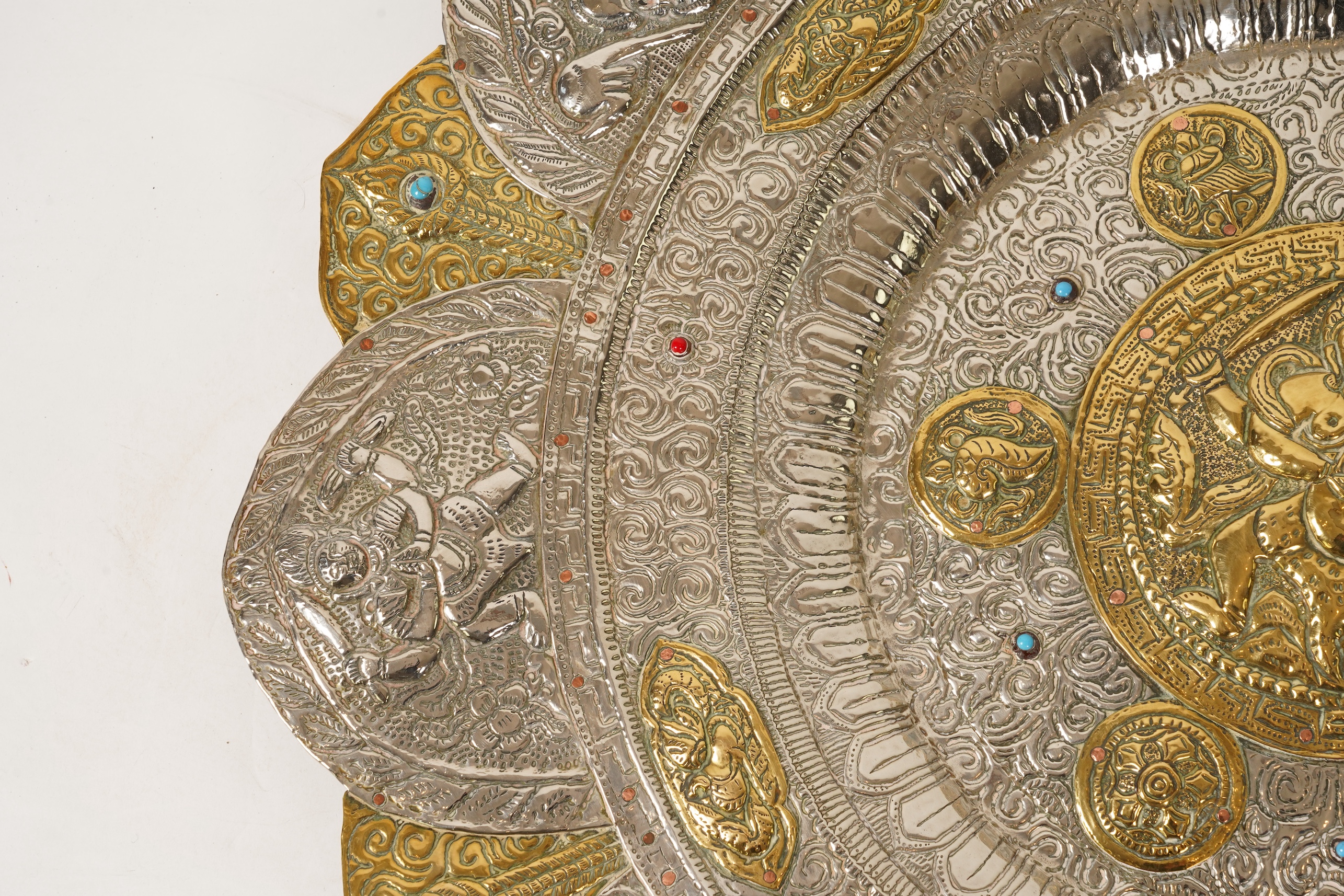 A graduated set of three Nepalese repoussé white metal and brass chargers, first half 20th century